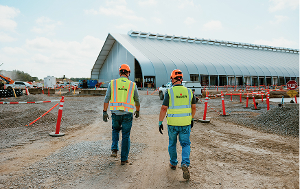 Construction workers walking towards a modern building at a Sauer Group project site.