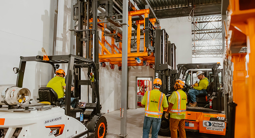 Industrial workers operating forklifts at Sauer Group facility.