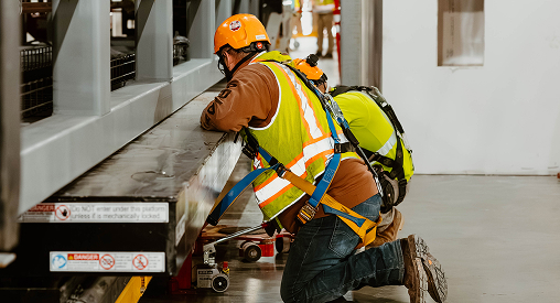 Worker inspecting machinery at industrial site.