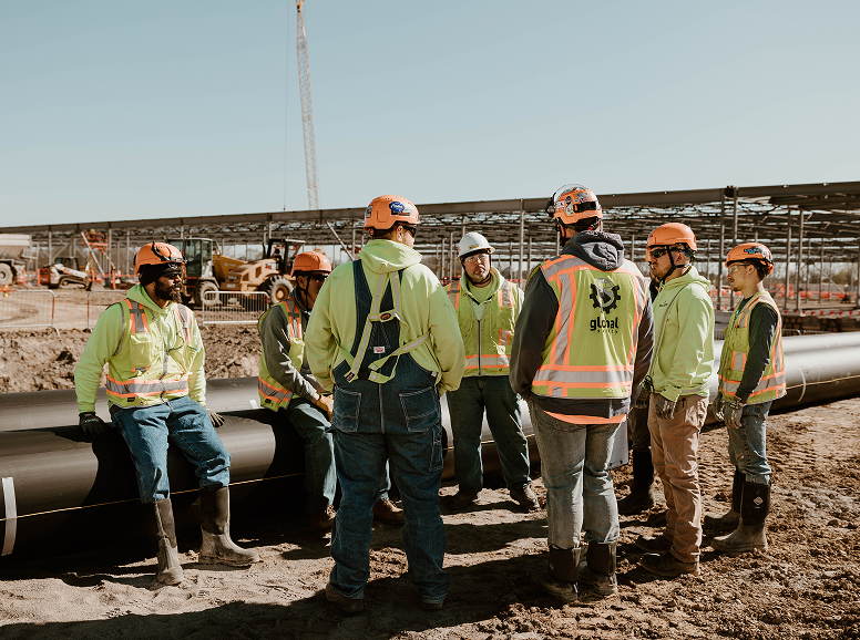 Pipeline construction team discussing project details outdoors.
