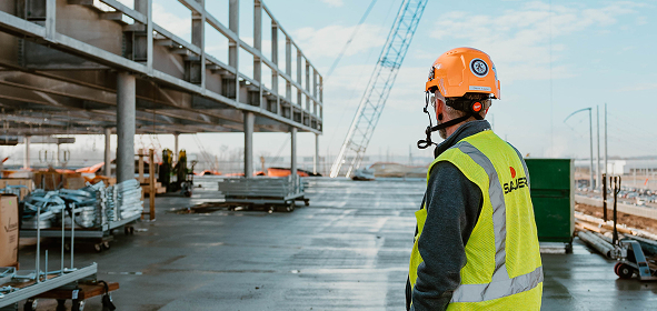 Construction worker wearing safety gear at a building site.