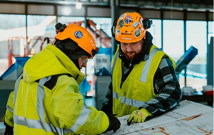 Two men in safety uniforms at a construction site.